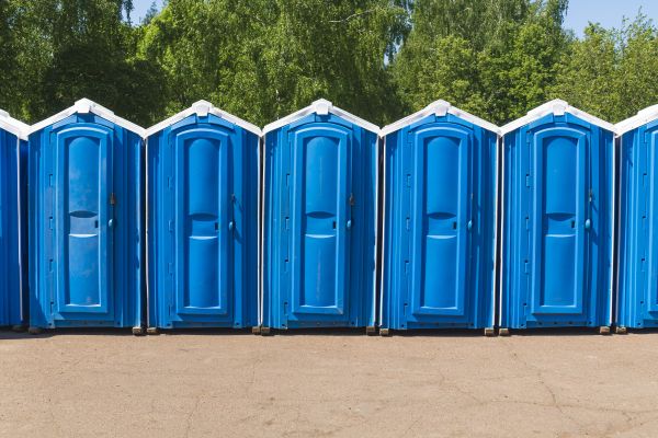 Jobsite porta potty rental beside construction equipment in Phoenix and Arizona